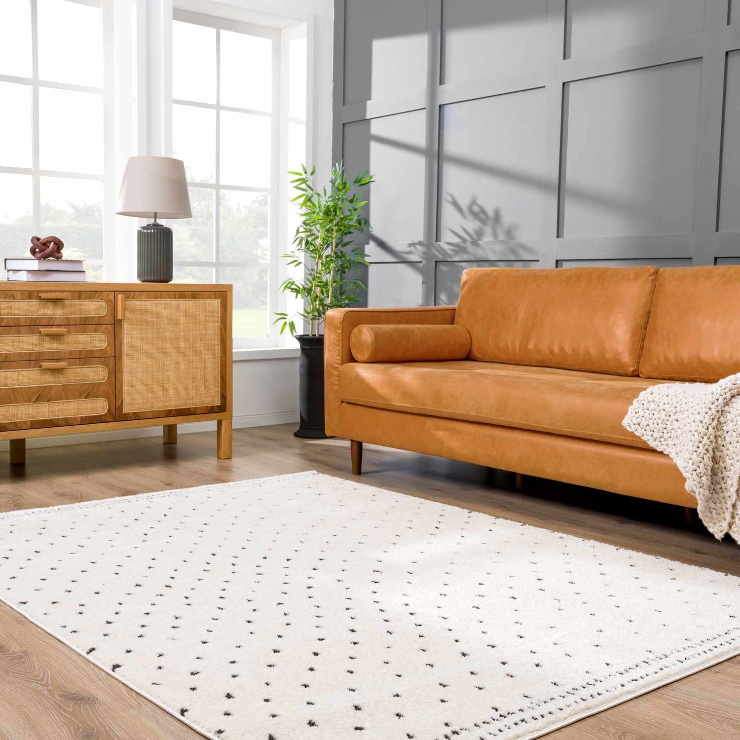 Living room with tan leather sofa and beige Julie Area Rug with black polka dot pattern. Roomscene-Rectangle