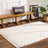 Entryway with Julie Area Rug: beige rug with black polka dots, wood bench, HOME pillow, and plant. Roomscene-Rectangle