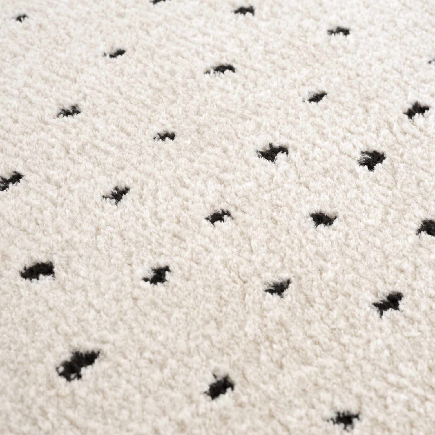 Close-up of the Julie Area Rug showing its beige shag texture and black polka dot pattern. Texture