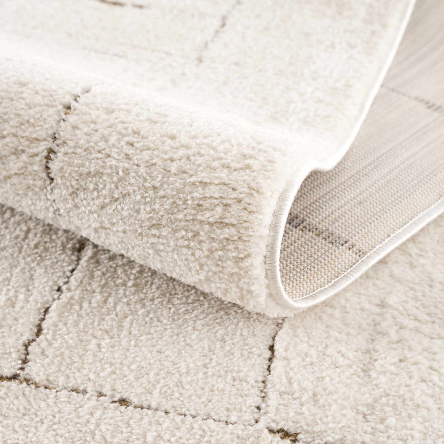 Close-up of the beige Keats Area Rug showing its soft, textured pile and geometric line pattern. Fold