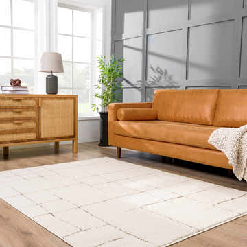 Living room scene with a Koume Ivory & Brown Area Rug, tan leather sofa, and wood cabinet. Modern, bright, and stylish. Roomscene-Rectangle