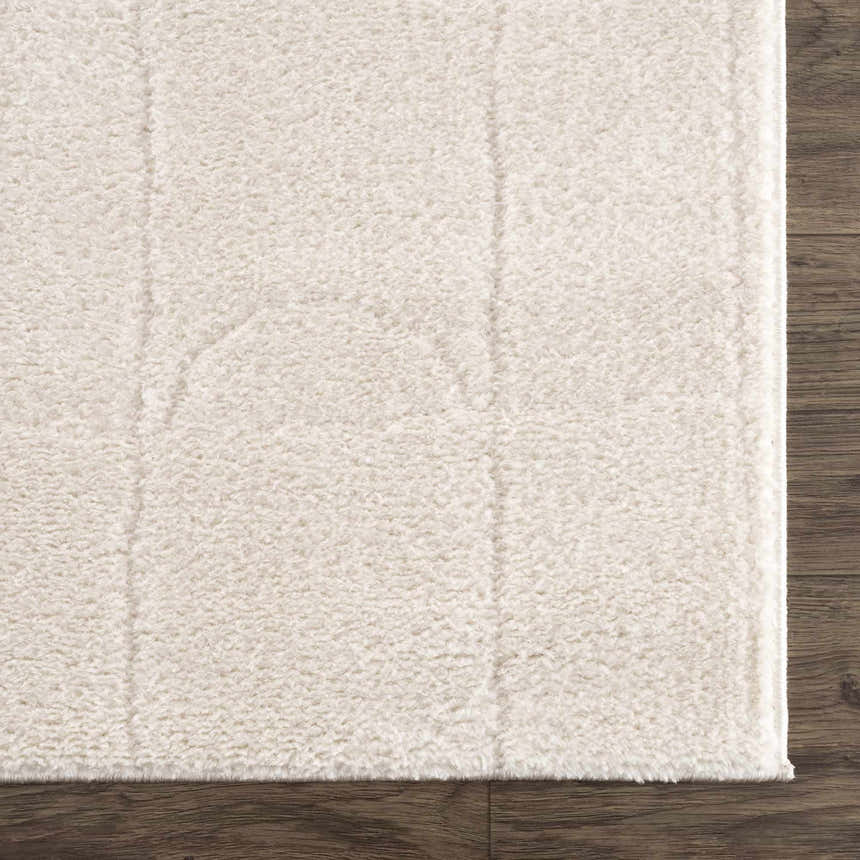 Close-up of the ivory Keanu rug showing its plush texture and subtle linear pattern on dark wood flooring. Swatch