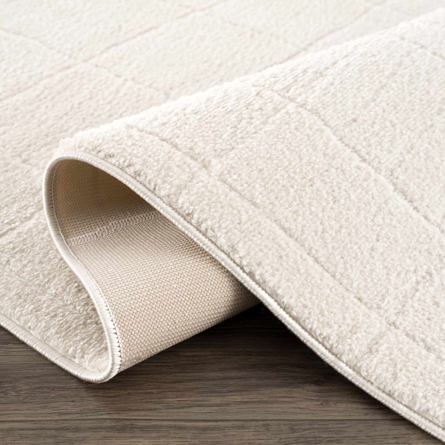 Close up of the ivory Keanu Area Rug showing texture, backing, and woven construction. Fold