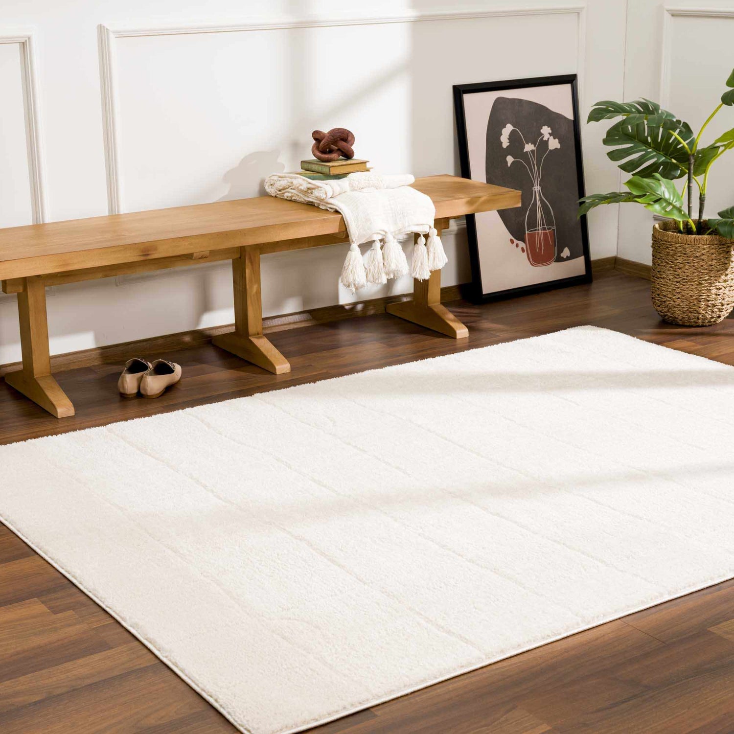 Entryway scene with a Keanu Ivory Area Rug, wood bench, art print, and plant. Warm and inviting. Roomscene-Rectangle