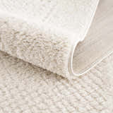 Close-up of the plush, ivory Julio Area Rug showing its soft texture and machine-woven construction. Fold