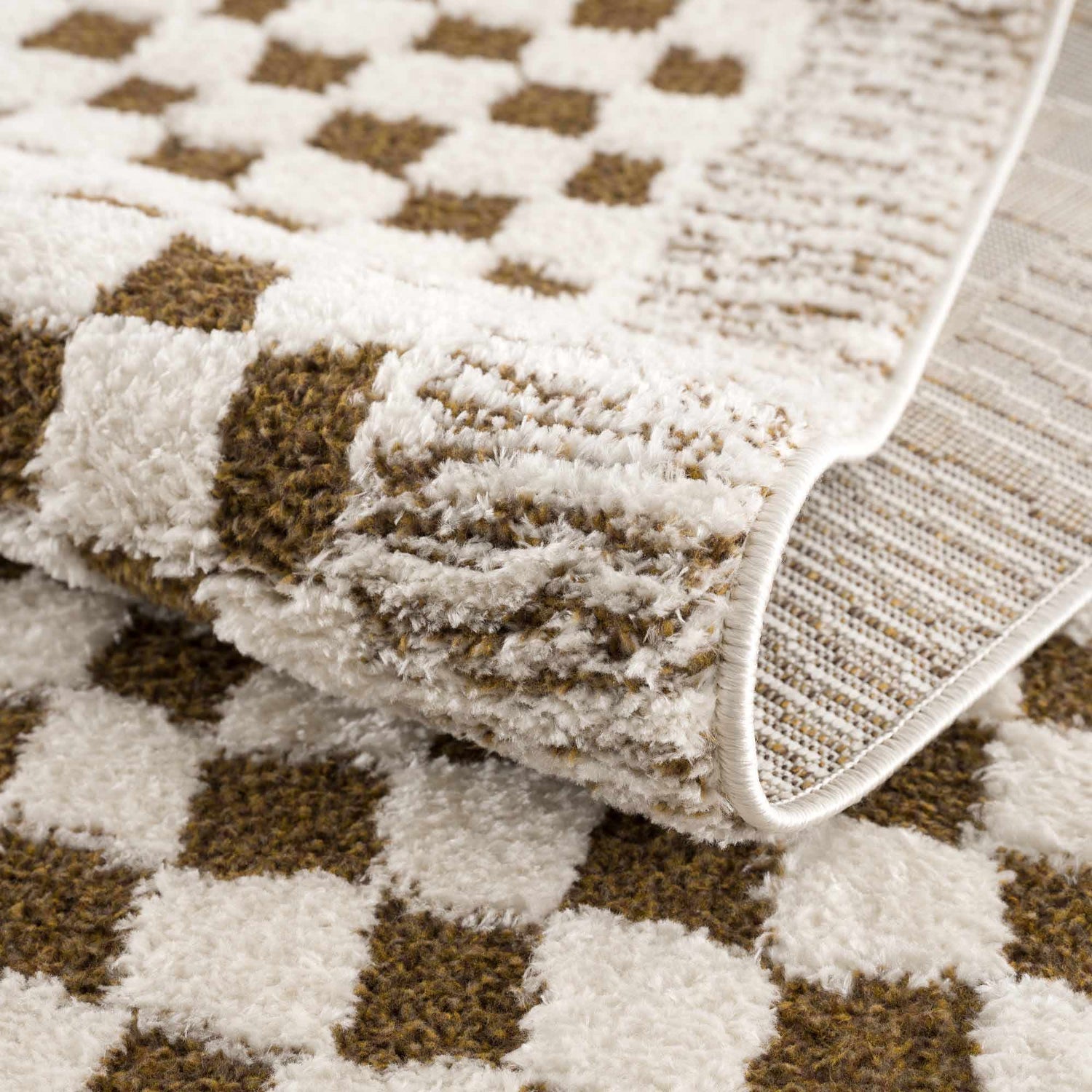 Close up of the Leryn Brown Checkered Plush Rug showing its plush texture and brown and ivory geometric pattern. Fold