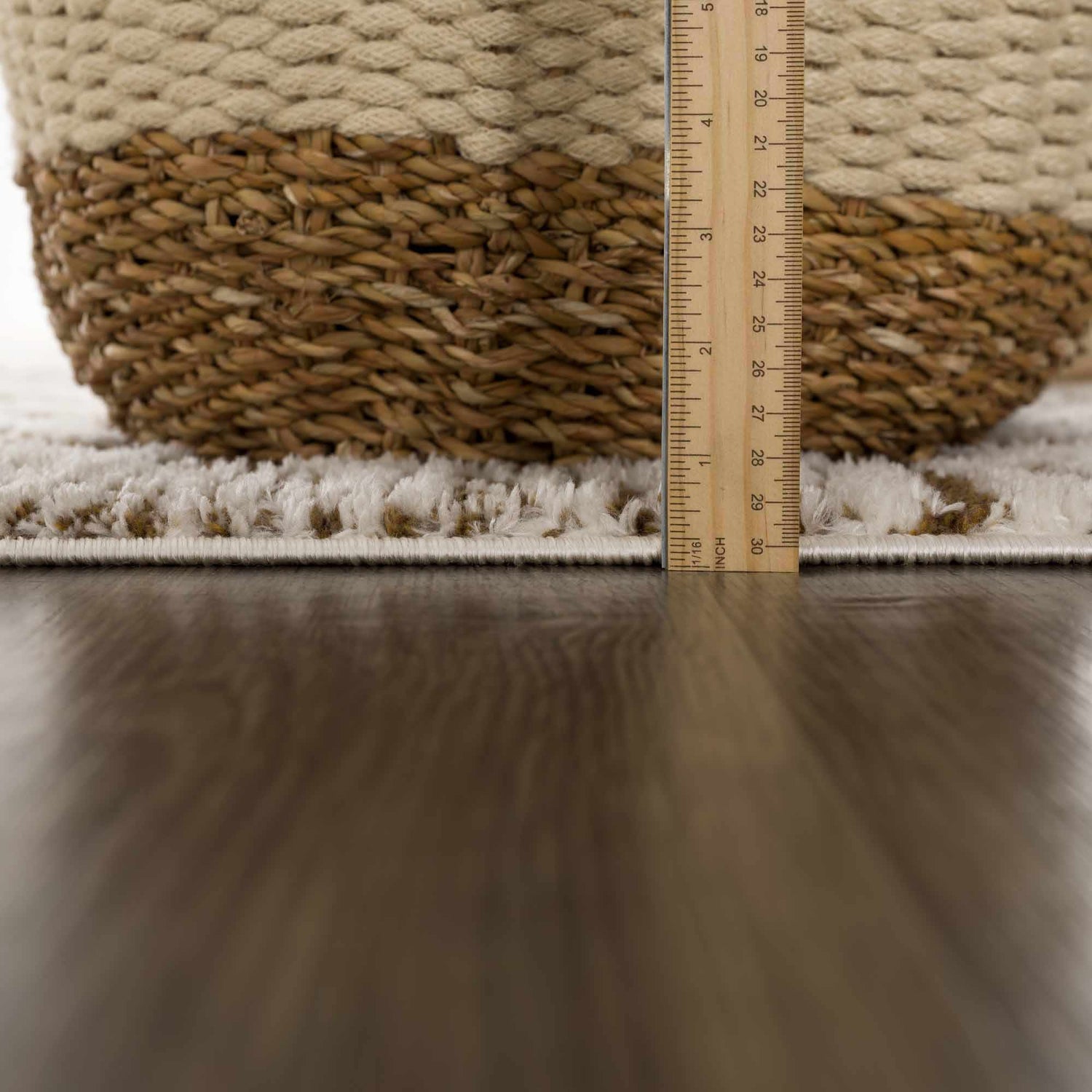 Close-up of the plush Leryn Brown Checkered Rug, showing its thickness with a ruler next to a woven basket. Pile