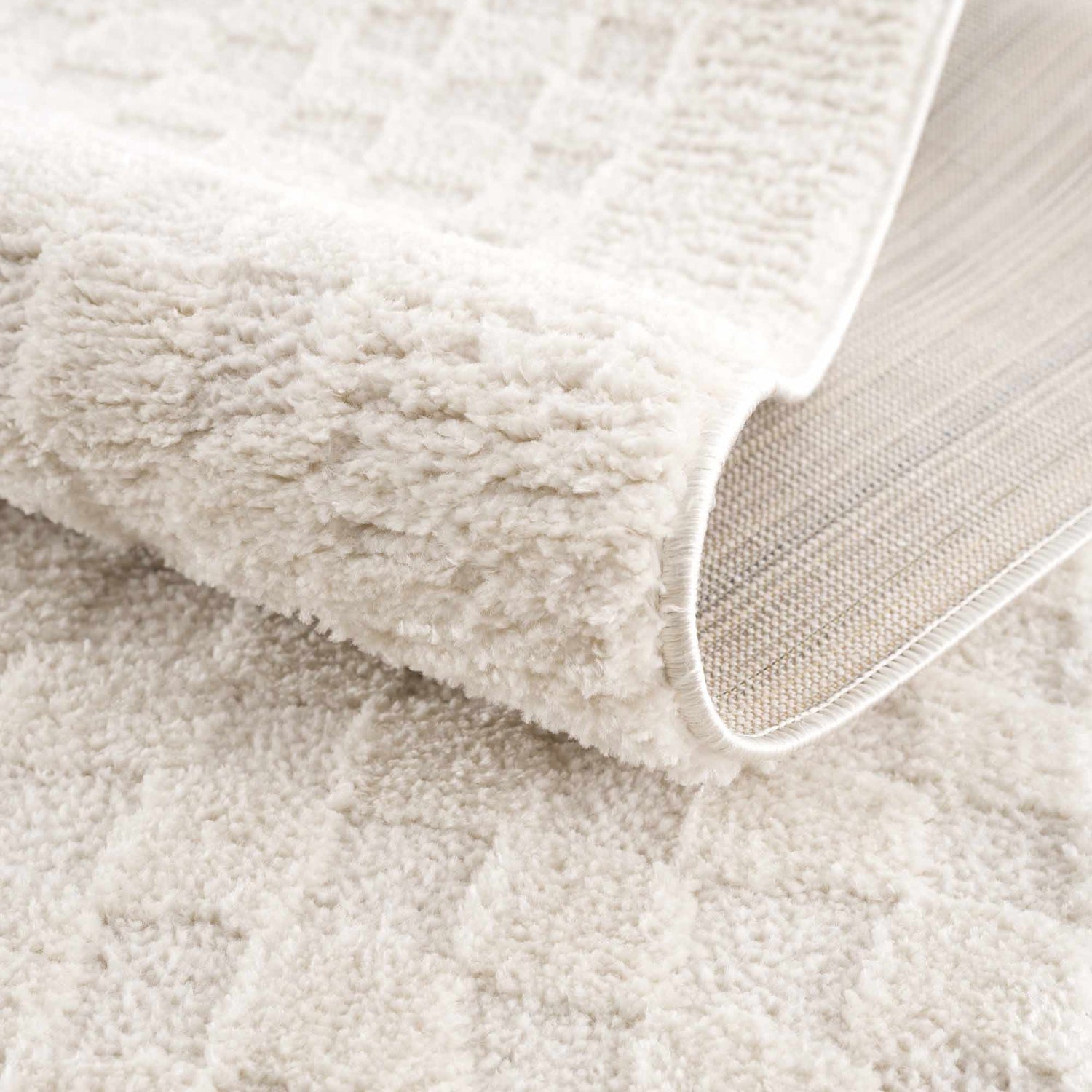 Close-up of the plush, ivory Leryn Ivory Checkered Area Rug showing its geometric checkered pattern and woven backing. Fold