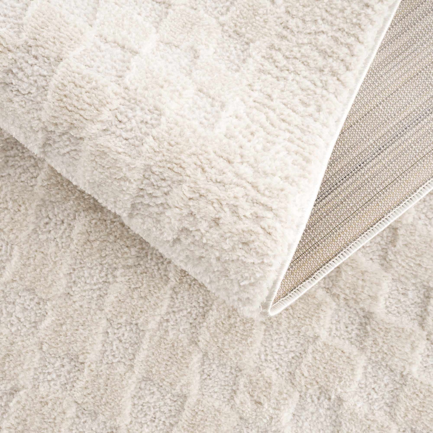 Close-up of the plush Leryn Ivory Checkered Area Rug showing the soft texture and geometric checkered design. Fold