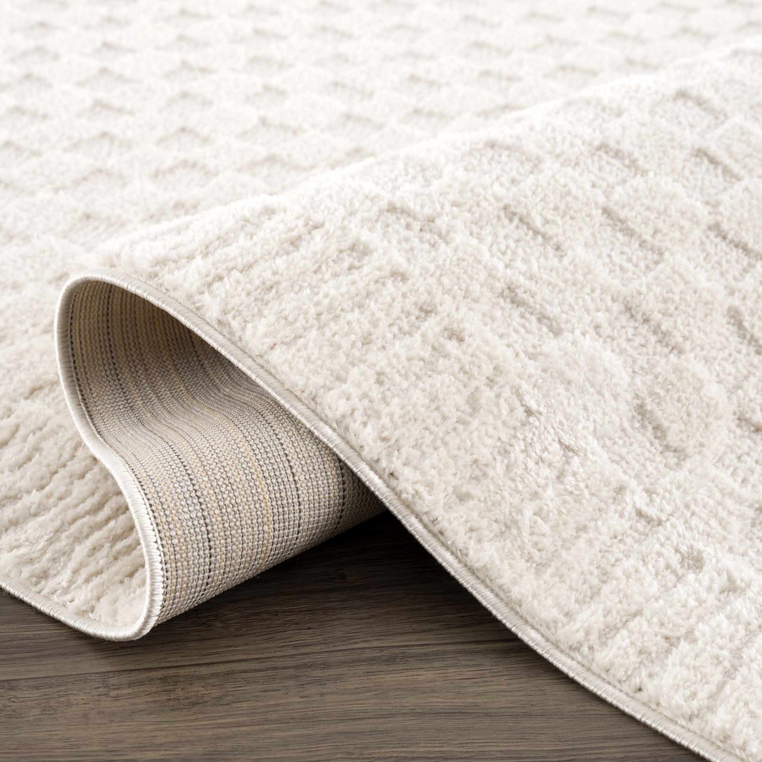 Close-up of the Leryn Ivory Checkered Area Rug showing its soft texture and geometric checkered pattern on a wood floor. Fold
