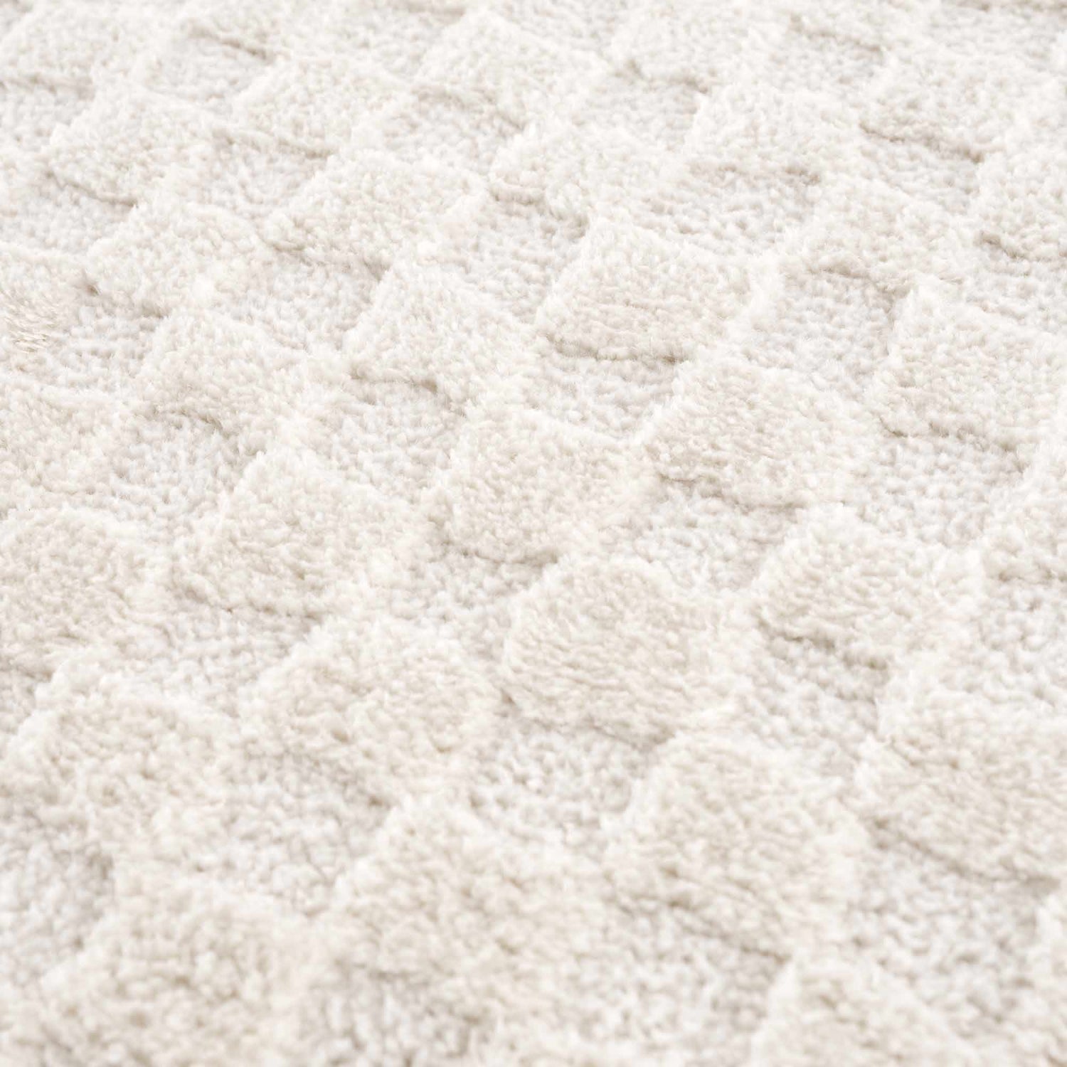 Close-up of the plush, ivory Leryn Ivory Checkered Area Rug. The rug features a textured, geometric checkered pattern. Texture