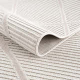 Close-up of the beige Lova Area Rug showing geometric pattern and textured, machine-woven construction. Fold
