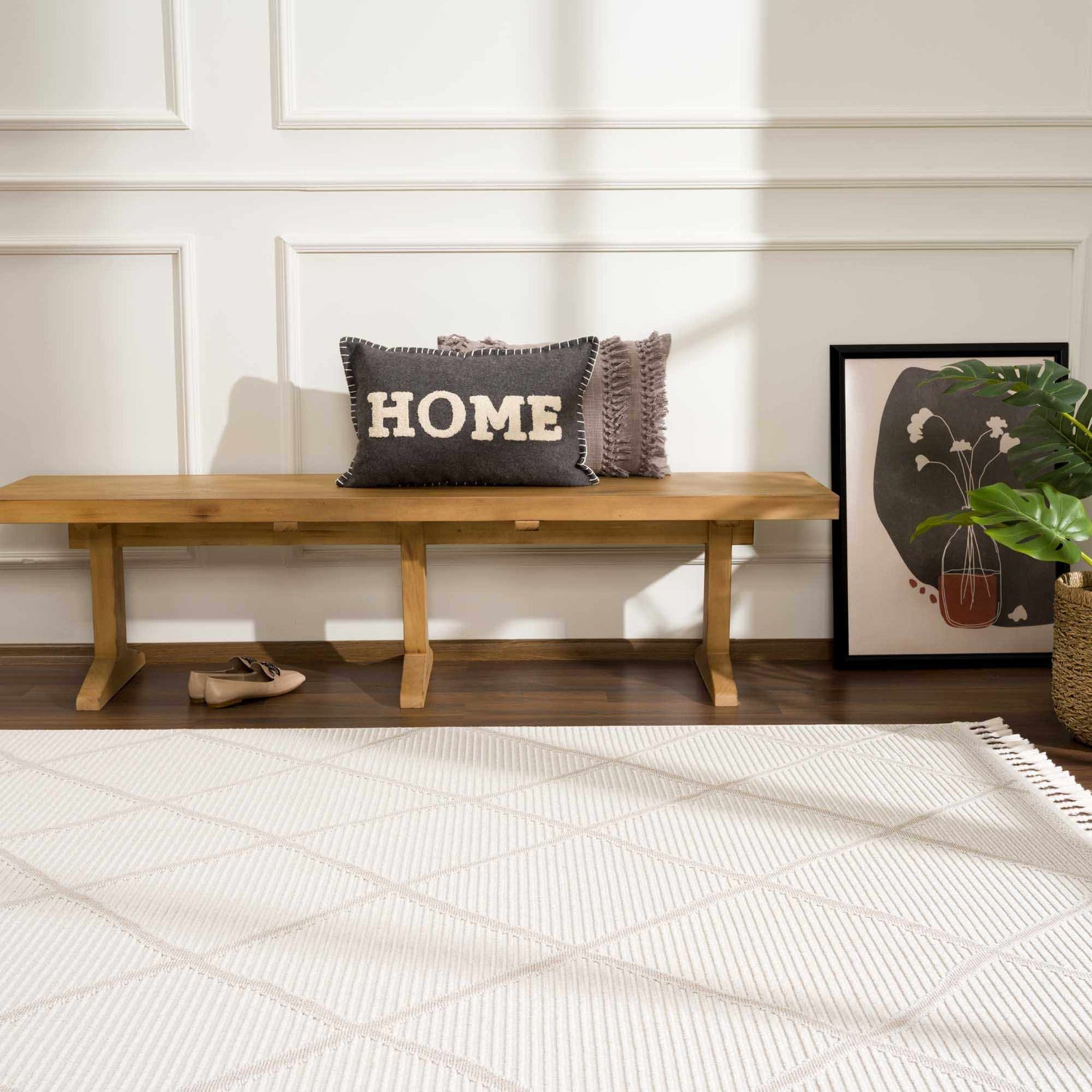 Entryway scene with a beige Lova Area Rug, wood bench, gray HOME pillow, and modern art. Roomscene-Rectangle