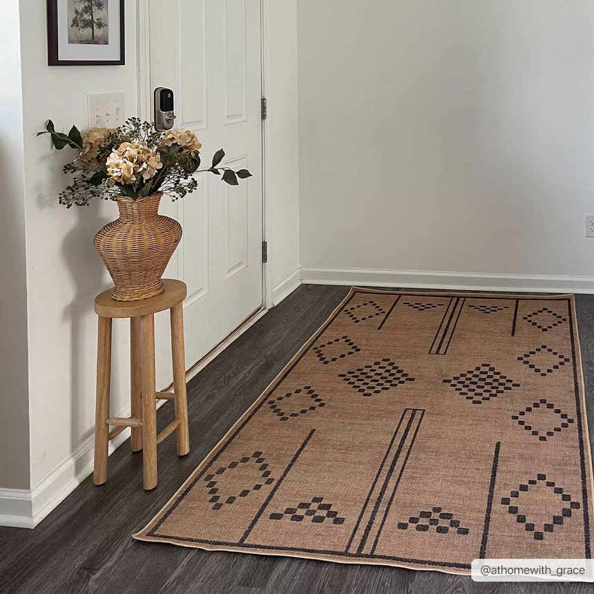 Entryway scene with Fathi Washable Area Rug in camel and brown. Farmhouse style with flowers and wood stool. Roomscene-Rectangle