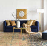 Living room scene with a blue sofa and the Duncansville Area Rug in aqua, pink, and brown tones. White brick wall. Styleshot