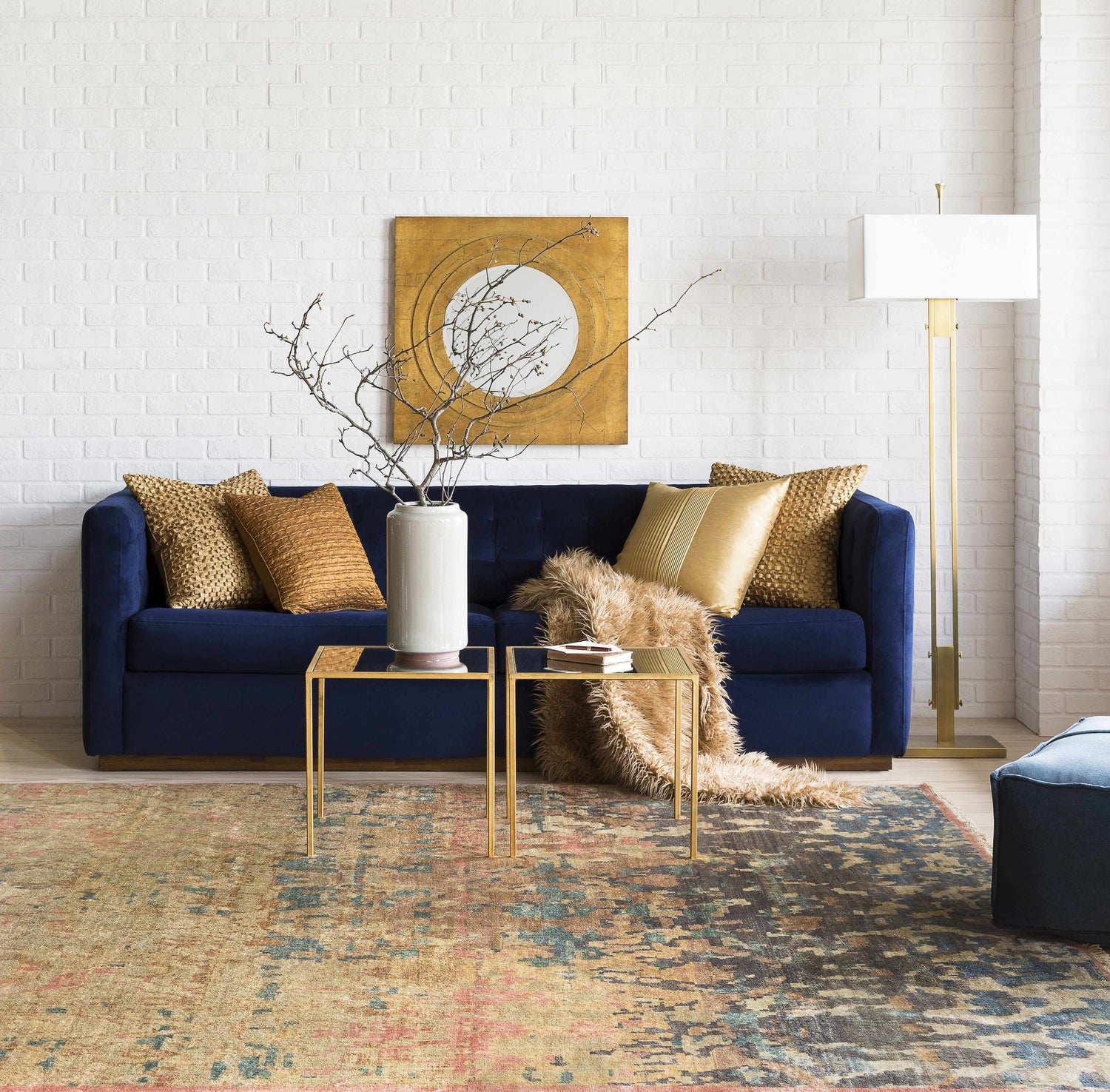 Living room scene with a blue sofa and the Duncansville Area Rug in aqua, pink, and brown tones. White brick wall. Styleshot