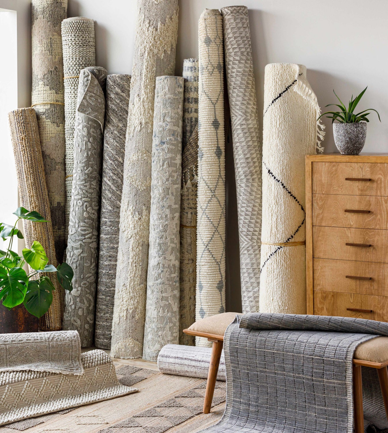 Rolled Cayuga Area Rugs in various textures and neutral colors, styled with a wood dresser and potted plant. Styleshot