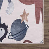 Close-up of the Libra Rainbow Kids Washable Area Rug showing planets, stars, and a beige, dark red, and terracotta color palette. Corner