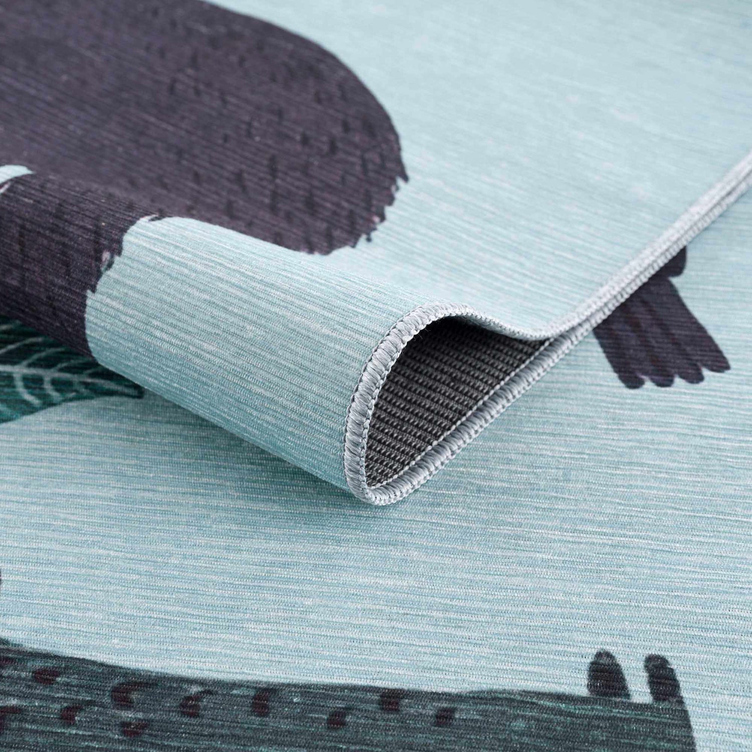 Close-up of the Petey Blue Animal Print Washable Kids Rug, showing aqua, navy, and burnt orange animal pattern and chenille texture. Fold