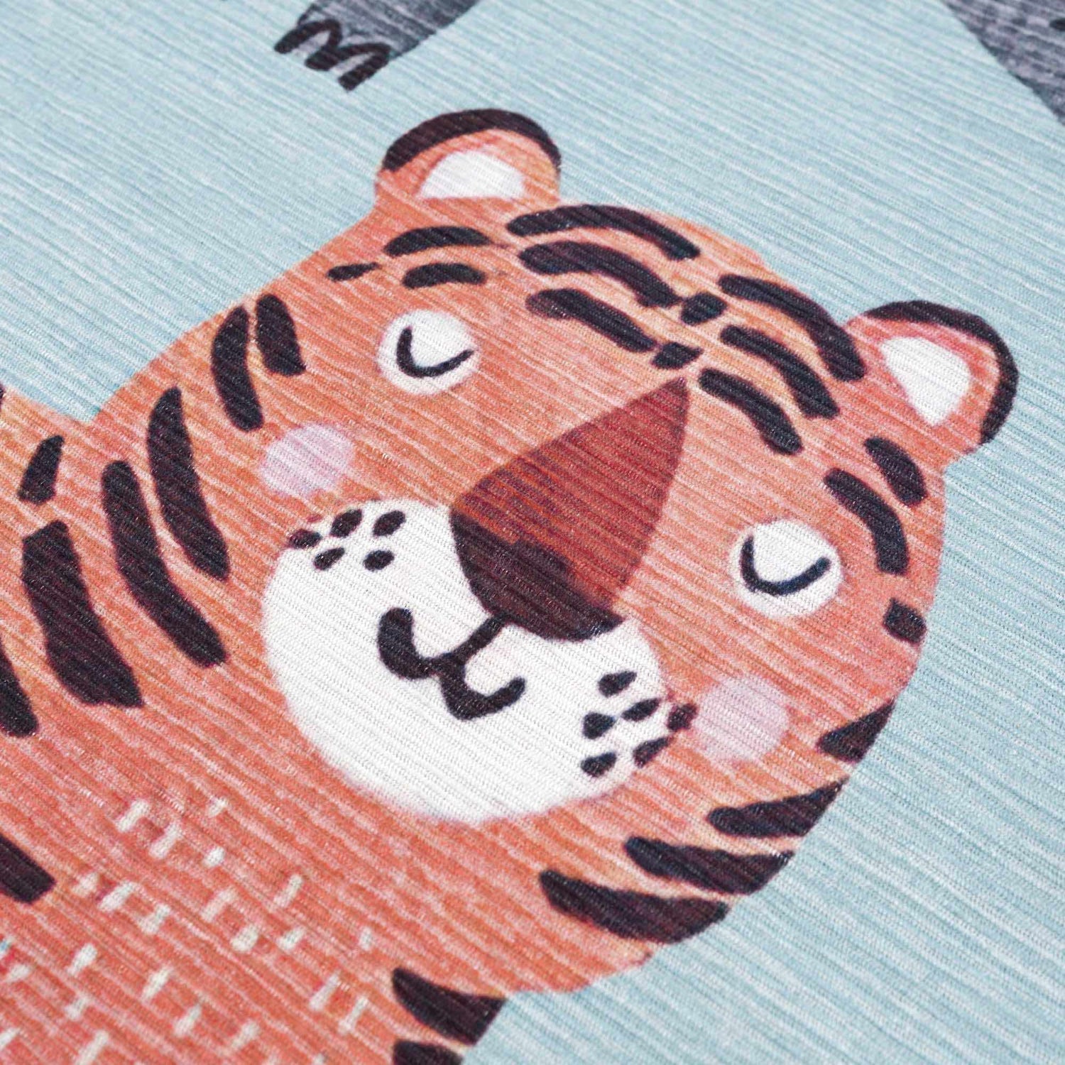Close up of the Petey Blue Animal Print Washable Kids Rug, featuring a tiger design in aqua, burnt orange, and navy. Texture