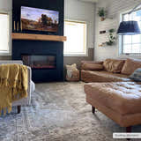 Living room with a brown leather couch and Gael Boutique Washable Rug in light blue, olive, tan, and yellow. Roomscene-Rectangle