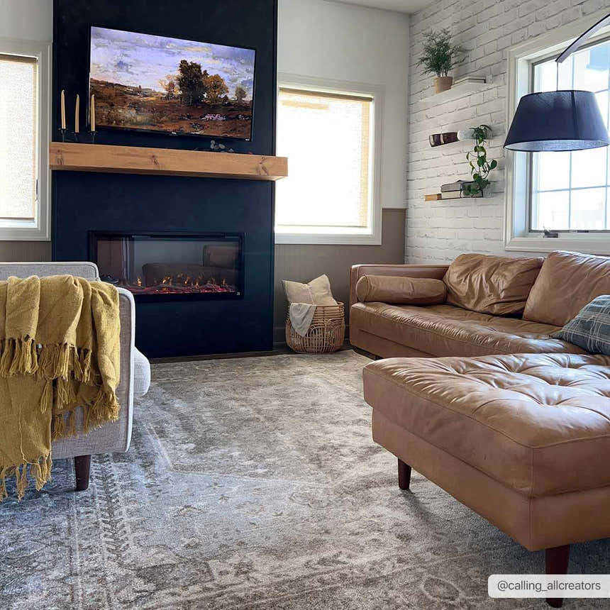 Living room with a brown leather couch and Gael Boutique Washable Rug in light blue, olive, tan, and yellow. Roomscene-Rectangle