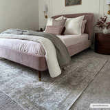 Bedroom scene with a light pink bed and a light gray Gael Boutique Washable Rug with a vintage design. Roomscene-Rectangle