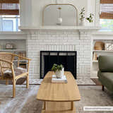Living room scene with a Gael Boutique Washable Rug, light wood coffee table, fireplace, and wicker chair. Roomscene-Rectangle