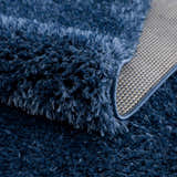 Close-up of the plush texture and backing of the Faina Solid Dark Blue Shag Washable Area Rug. Fold