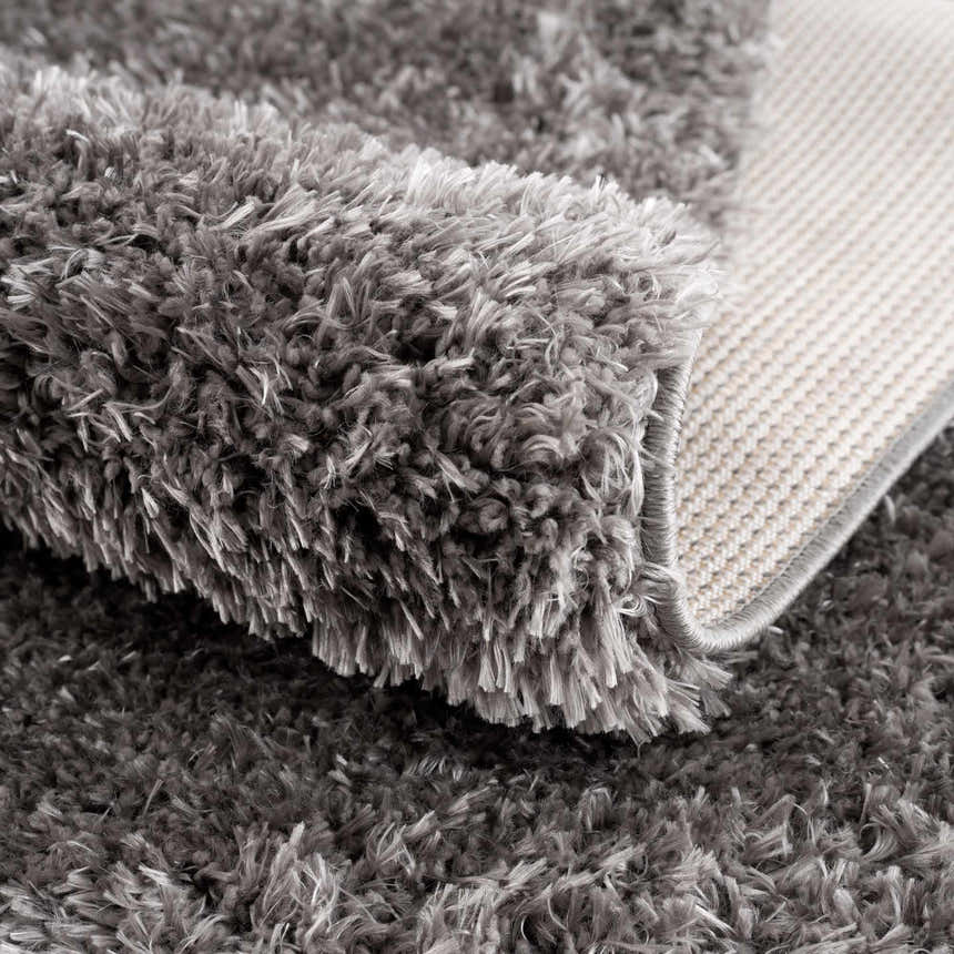 Close-up of the plush texture and backing of the Faina Solid Dark Gray Shag Washable Area Rug. Fold