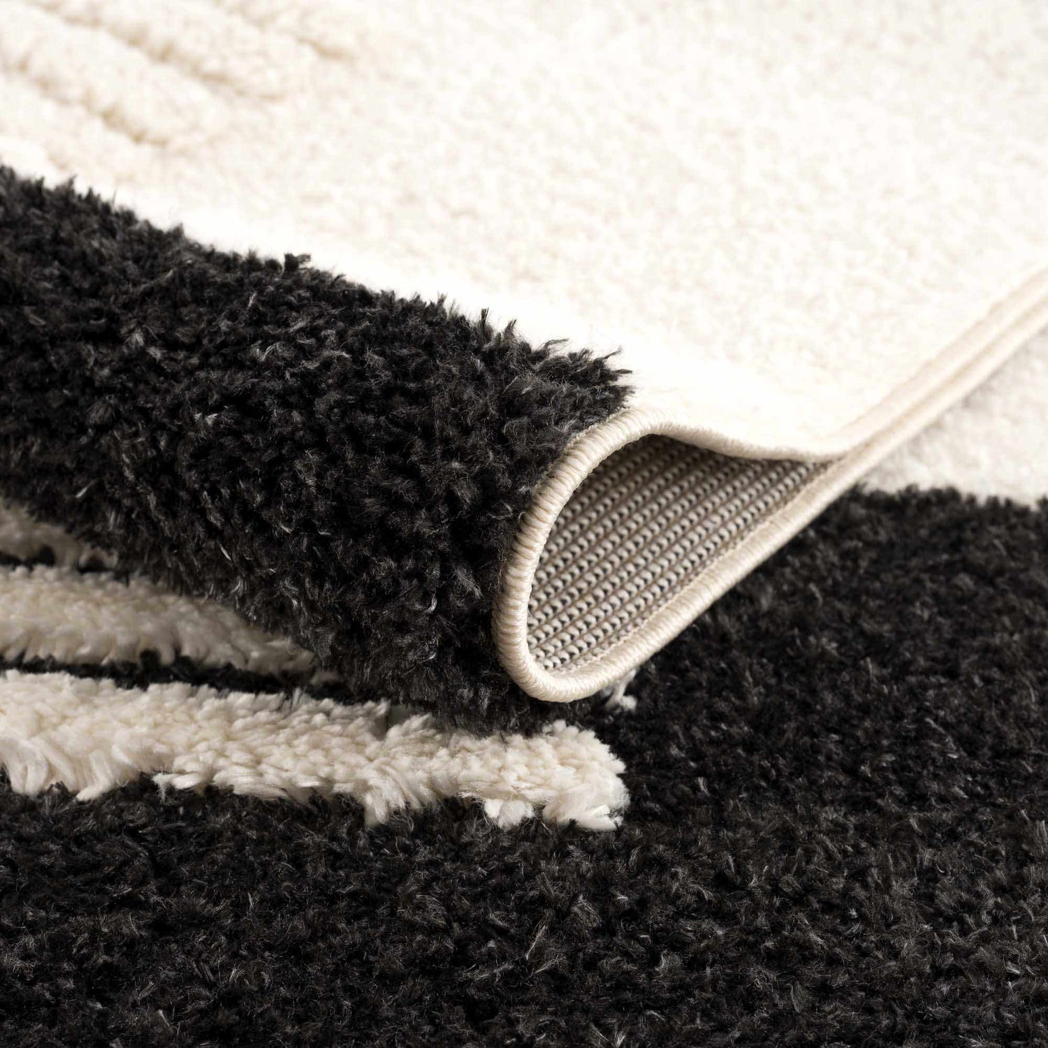 Close-up of the Astro Modern Shag Area Rug showing the black and white striped pattern and the texture of the shag pile. Fold