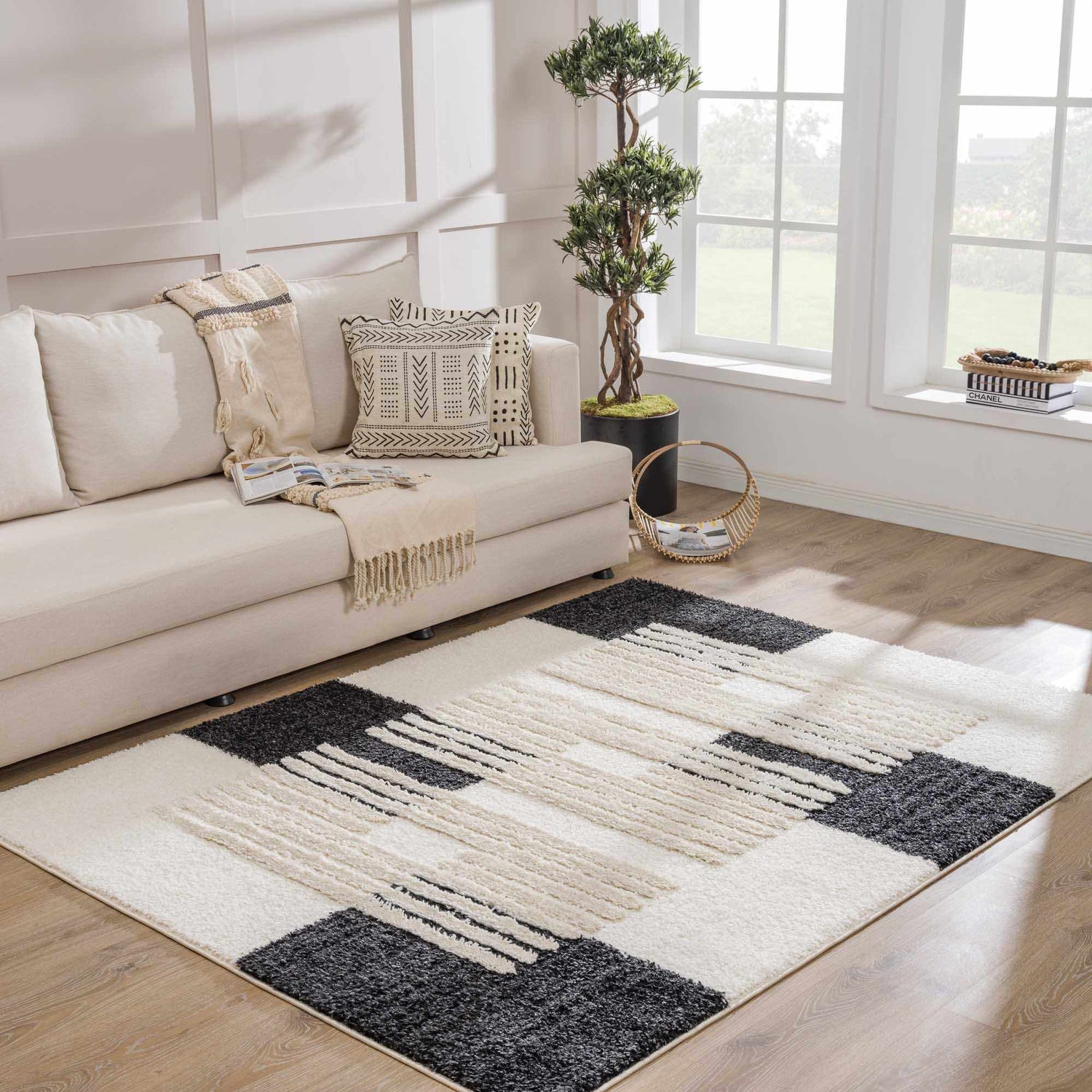 Living room scene with a neutral sofa and the Astro Modern Shag Area Rug in driftwood, faded driftwood, and onyx black. Roomscene-Rectangle