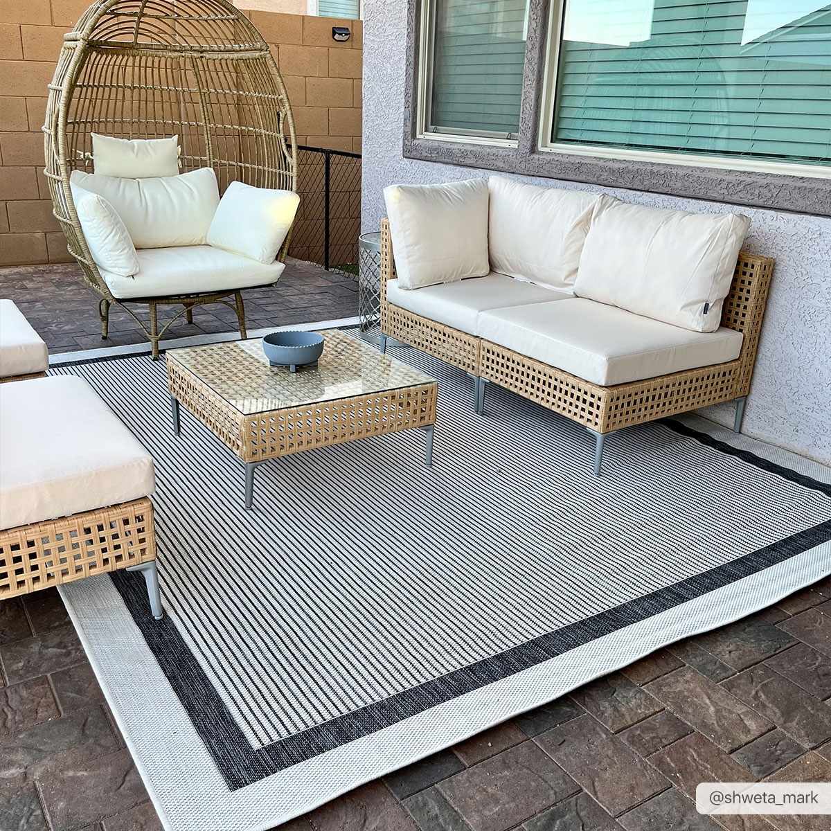 Outdoor patio scene with wicker furniture on a Hevel Black & White Area Rug. Modern, neutral tones. Roomscene-Rectangle