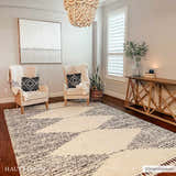 Living room scene with bone and dark gray Howth Area Rug, beige chairs, and wood accents. Roomscene-Rectangle