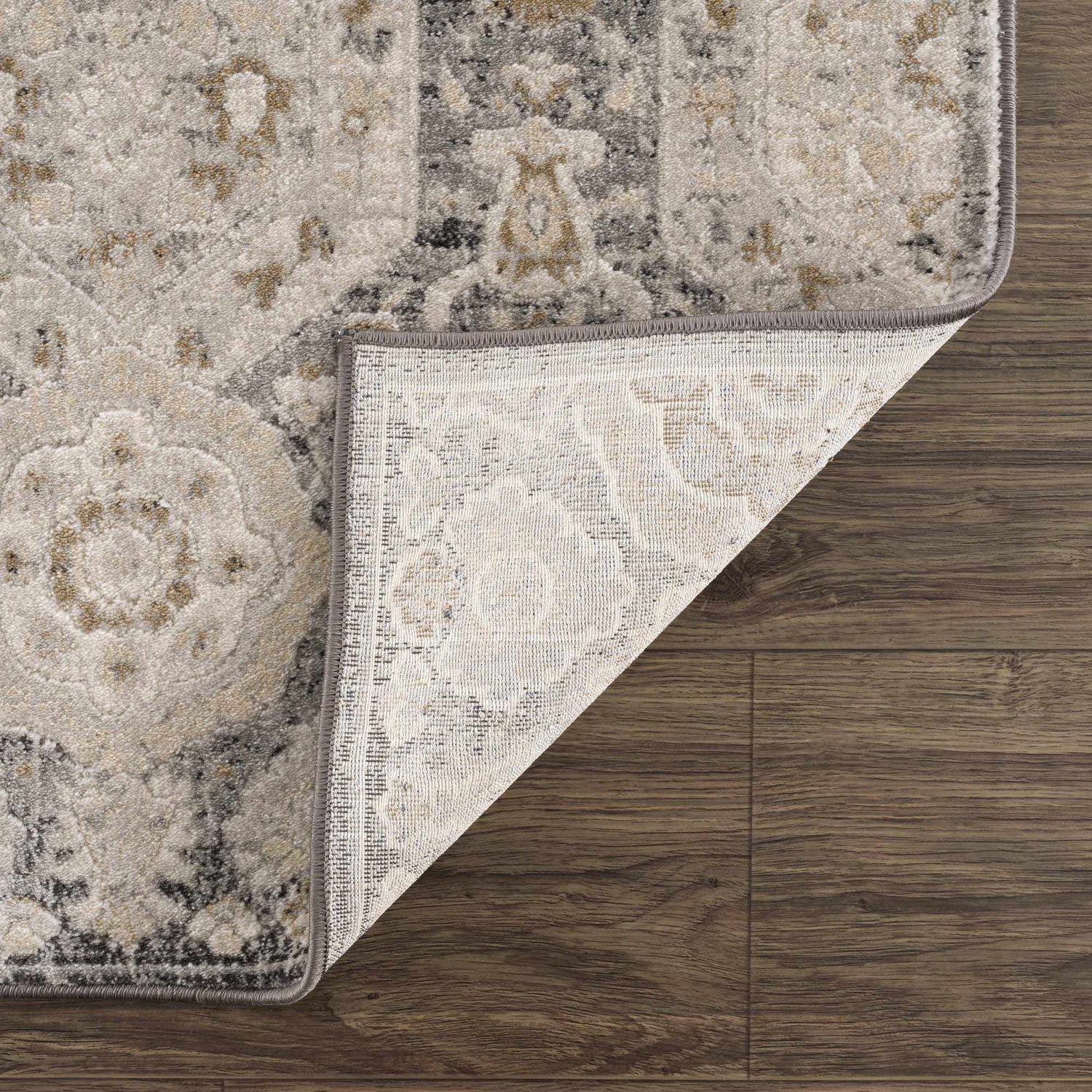 Close-up of the Minoa Area Rug showing its beige, black, and gray bohemian design and machine-woven construction. Fold