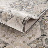 Close-up of the Minoa Area Rug showing its beige, gray, and black bohemian pattern and soft, machine-woven texture. Fold