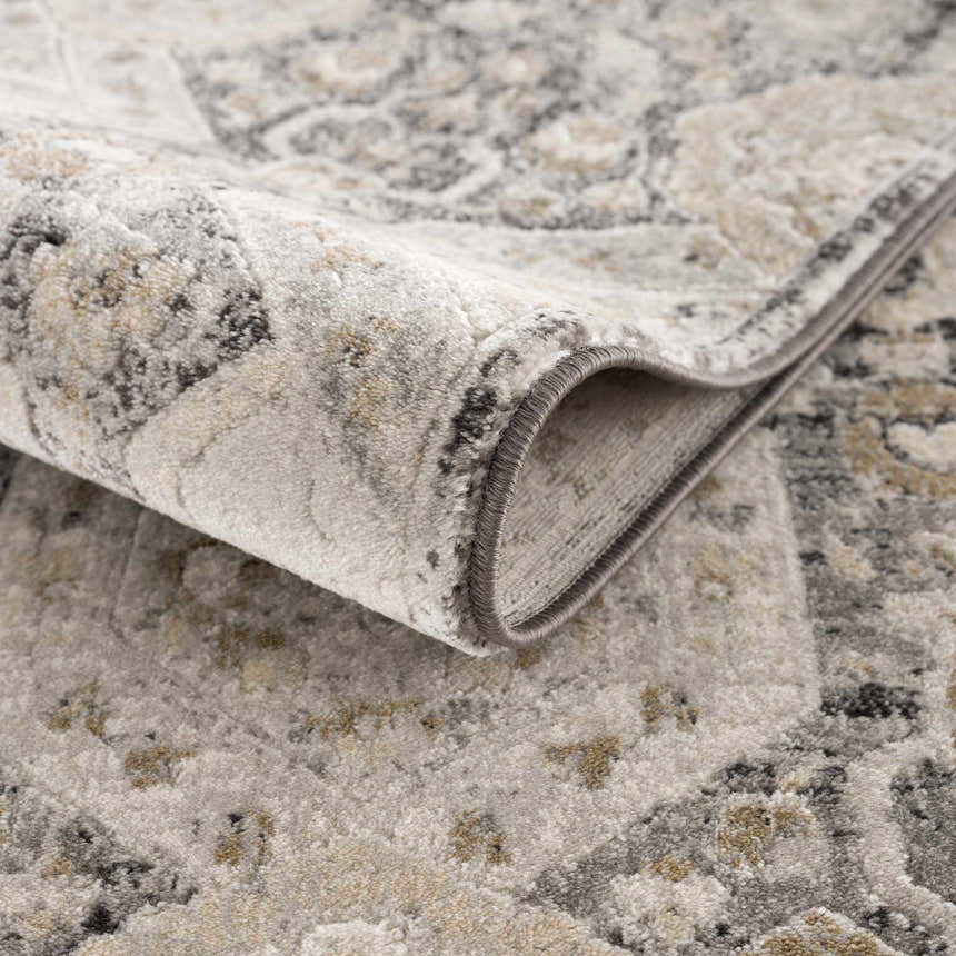 Close-up of the Minoa Area Rug showing its beige, gray, and black bohemian pattern and soft, machine-woven texture. Fold