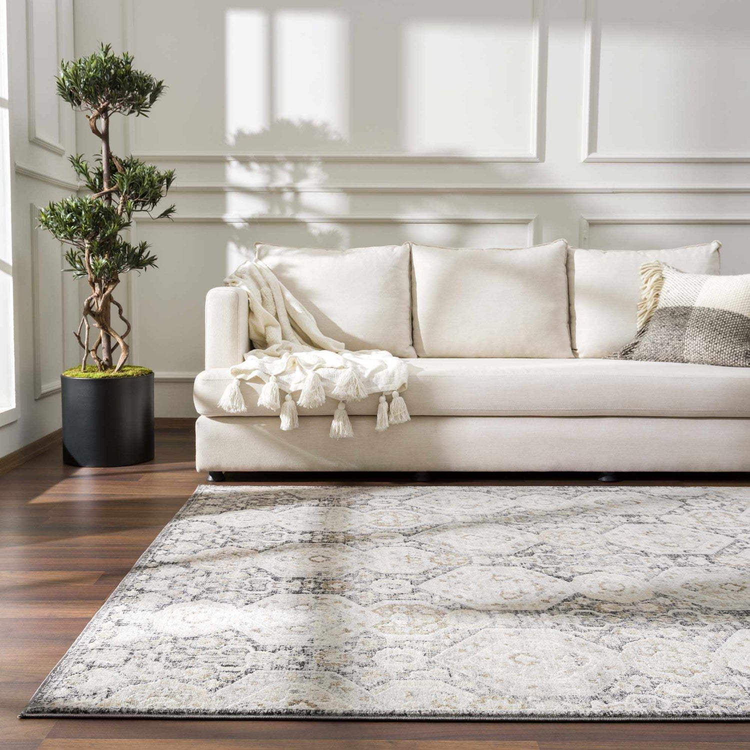 Living room scene with a beige sofa and the beige, black, and gray Minoa Area Rug on a dark wood floor. Roomscene-Rectangle