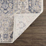 Close-up of the Parkerfield Cream & Blue Area Rug showing its floral pattern, texture, and backing on dark wood floor. Fold