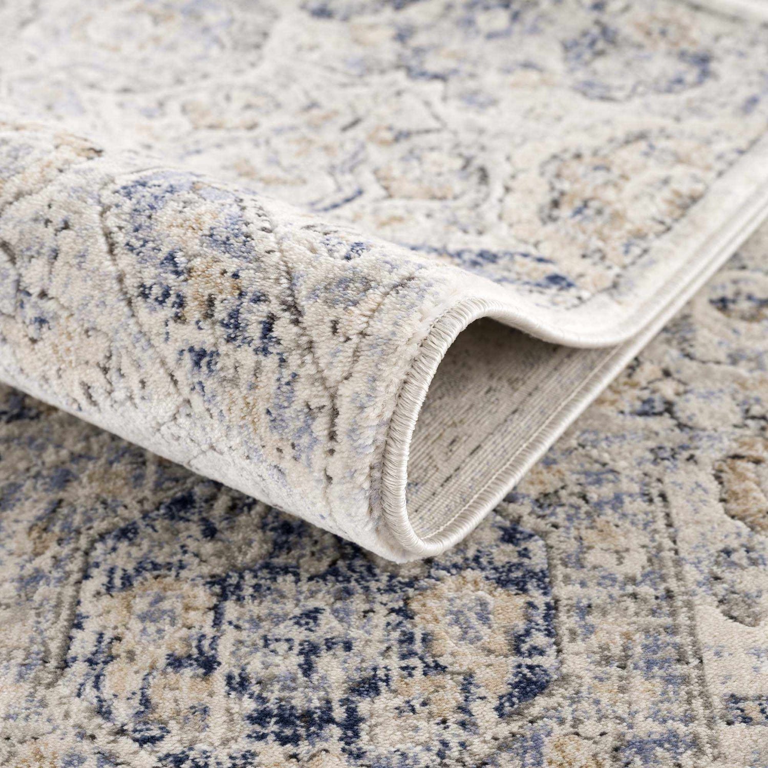 Close-up of the Parkerfield Cream & Blue Area Rug showing its soft texture and bohemian-inspired beige, blue, and cream pattern. Fold