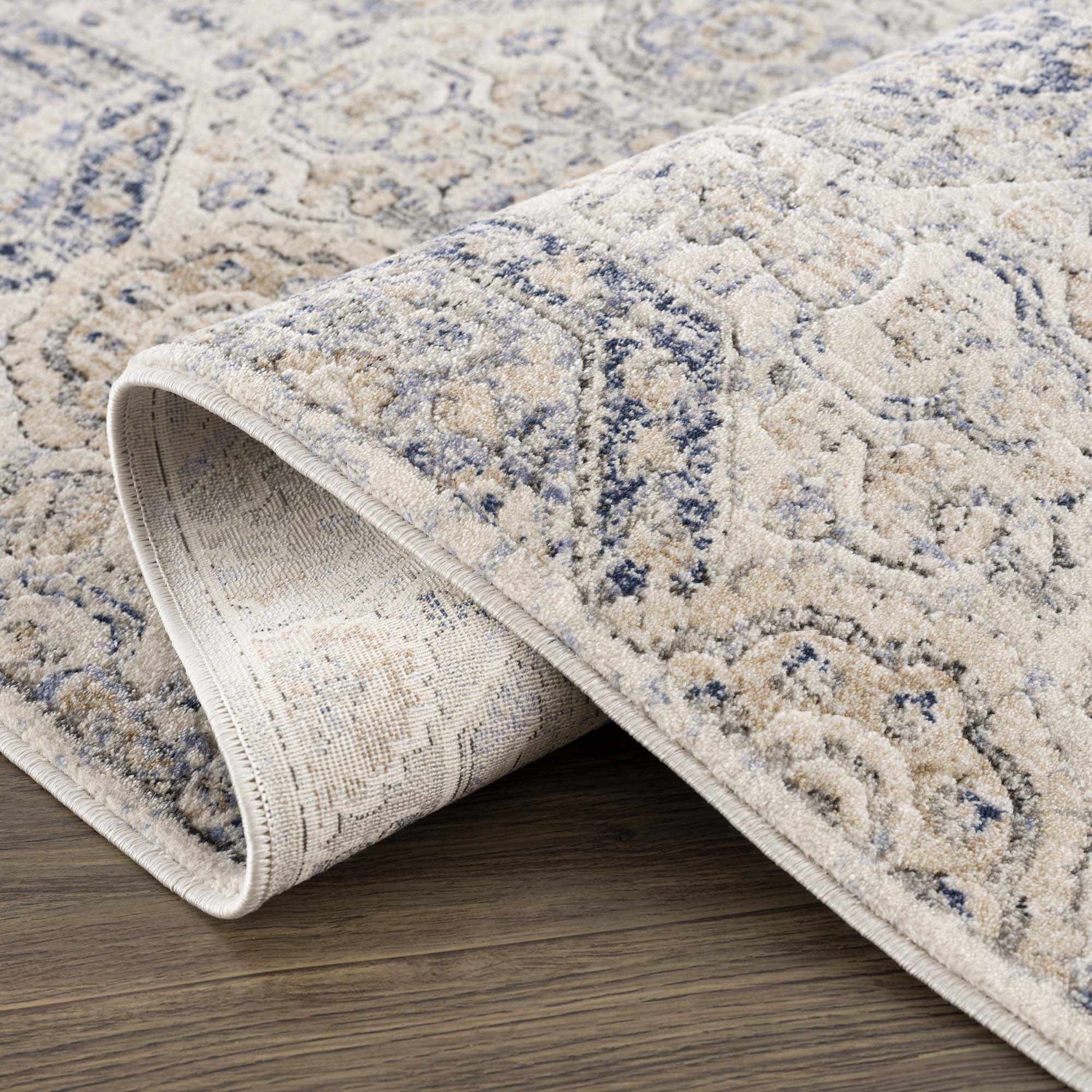 Close-up of the Parkerfield Cream & Blue Area Rug showing its traditional floral pattern and soft, neutral color palette. Fold