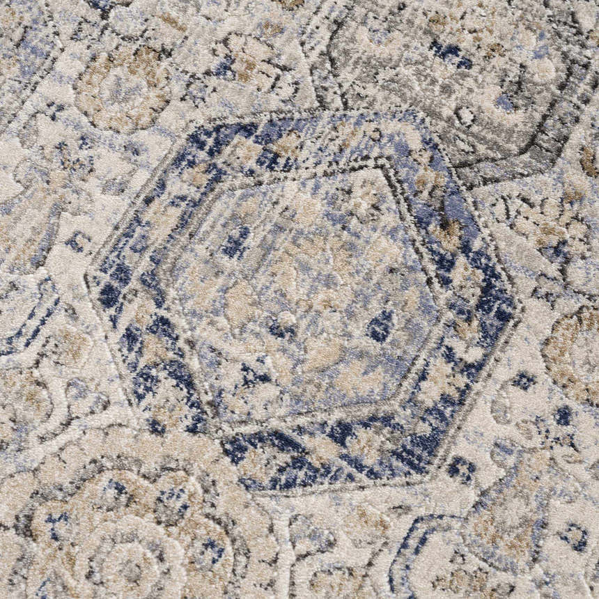 Close-up of the Parkerfield Cream & Blue Area Rug. Features a geometric, floral pattern in beige, navy, and gray hues. Texture