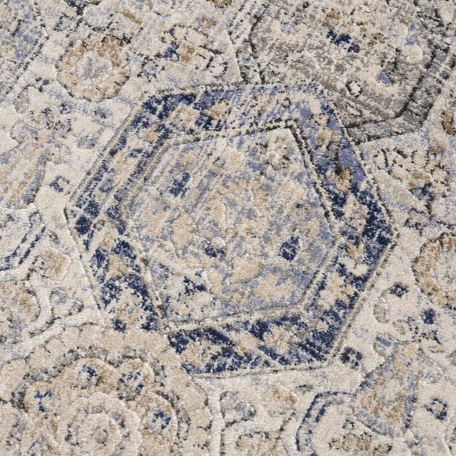 Close-up of the Parkerfield Cream & Blue Area Rug. Features a geometric, floral pattern in beige, navy, and gray hues. Texture