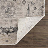 Close-up of Georgiana Area Rug showing beige, black, and gray floral pattern and machine woven construction on wood floor. Fold
