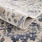 Close-up of the Georgiana Blue & Beige Oushak Rug showing its floral pattern, soft texture, and rolled edge. Fold