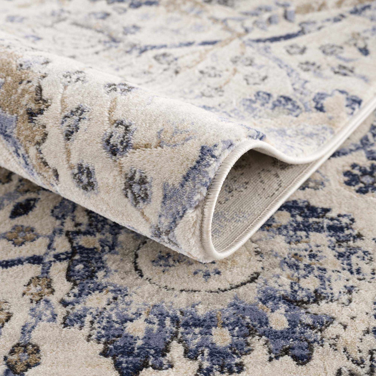 Close-up of the Georgiana Blue & Beige Oushak Rug showing its floral pattern, soft texture, and rolled edge. Fold