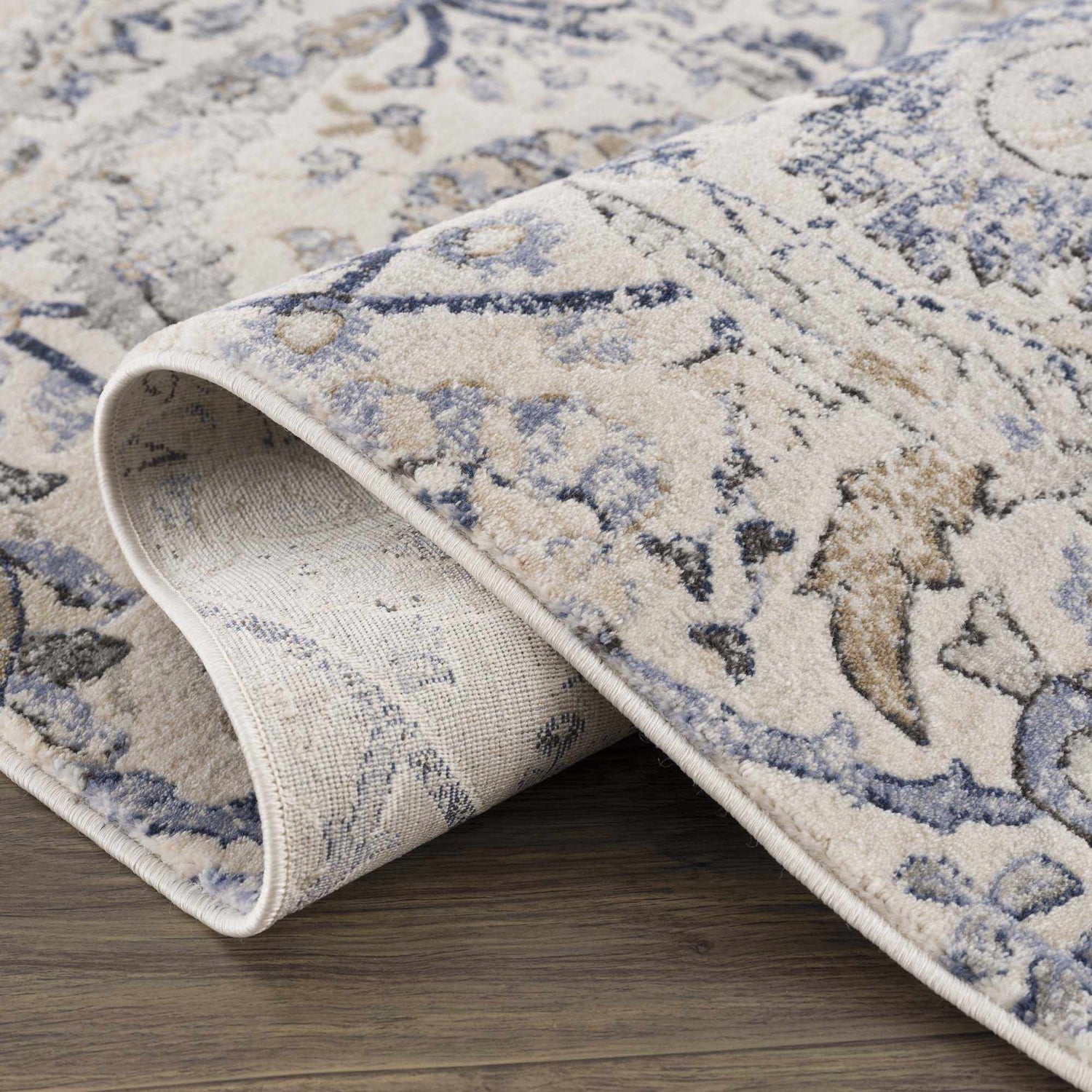 Close-up of the Georgiana Blue & Beige Oushak Rug showing its floral pattern, soft texture, and durable machine-woven construction. Fold