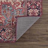 Close-up of the Neyland Area Rug showing its traditional red, blue, and beige pattern and machine-woven construction. Fold