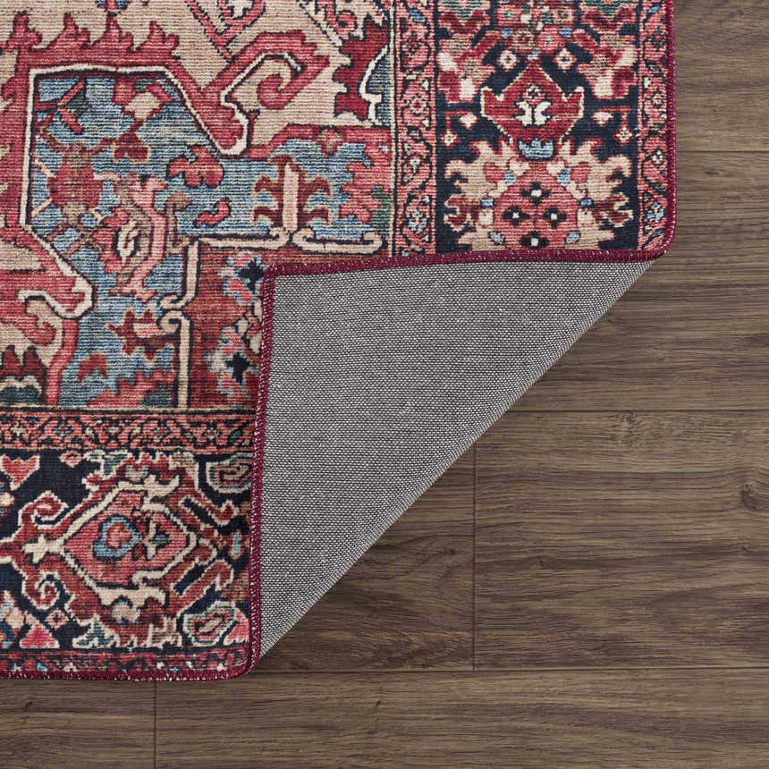 Close-up of the Neyland Area Rug showing its traditional red, blue, and beige pattern and machine-woven construction. Fold