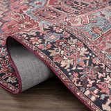 Close-up of the Neyland Area Rug showing its traditional red, beige, and blue Oriental pattern and machine-woven construction. Fold